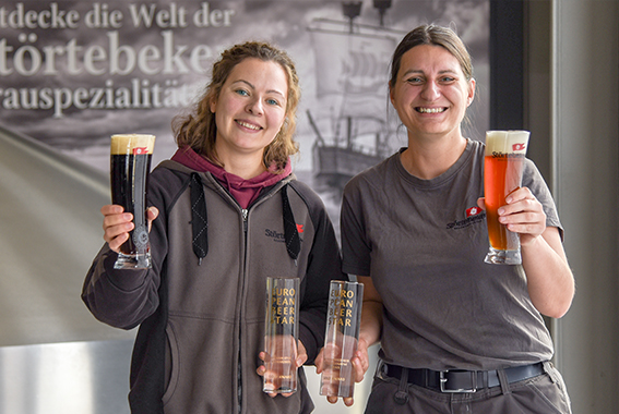 Die Störtebeker Mitarbeiterinnen Christina Holzner und Juliane Eiser freuen sich über die 2 Goldmedaillen für das Schwarz-Bier und das Roggen-Weizen beim European Beer Star 2024.